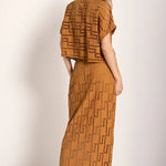 Image of a woman wearing an embroidered set. She is looking to the side and giving her back to the camera. The purpose of this image is to highlight the skirt and shirt.