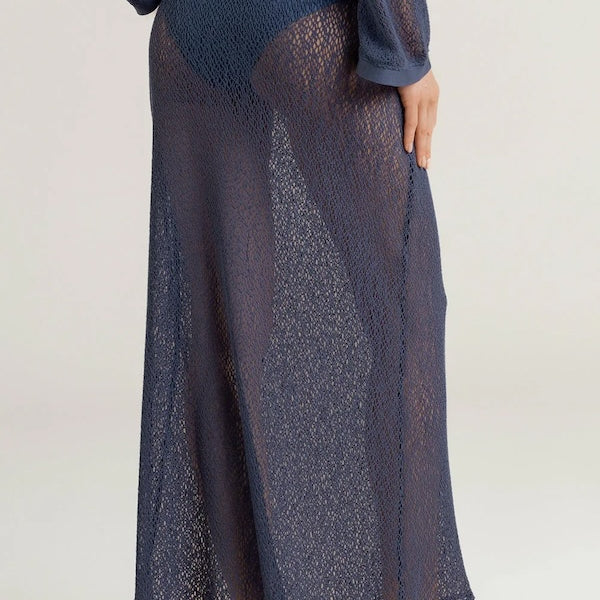 Person wearing a dark blue sheer maxi skirt with a plain background.