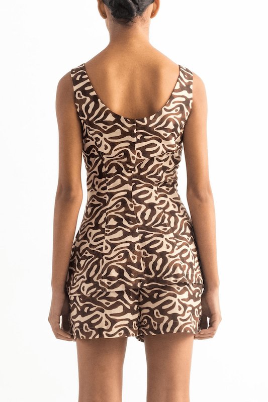 Image of the back of a woman wearing a brown vest with matching shorts. The background is white. This image helps us notice the fit of the clothing described.