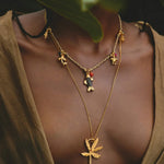 Gold necklace with leaf pendant worn by a woman, with a blurred background