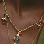 Necklace with fish charm and gold chain on a person's neck