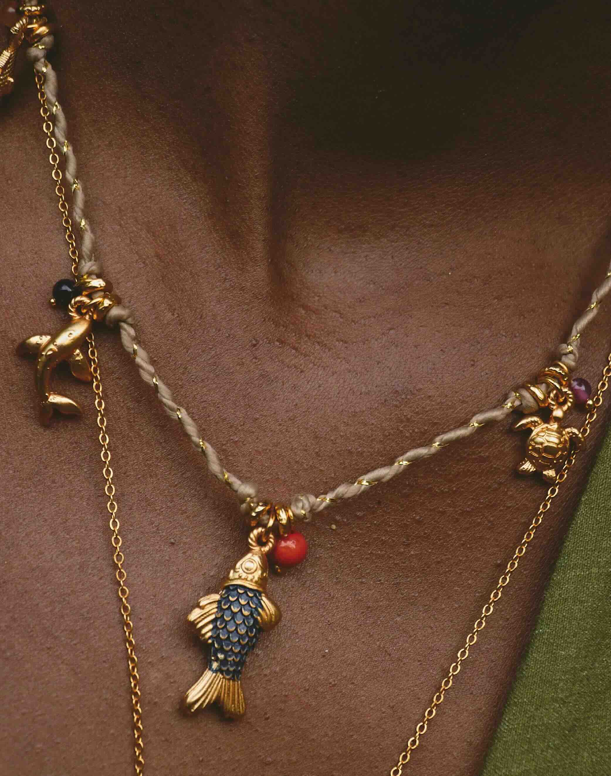 Necklace with fish charm and gold chain on a person's neck