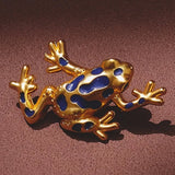 Gold frog brooch with blue spots on a brown background