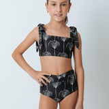 Girl wearing a black and white bikini set. She's standing behind a white background. The purpose of this image is to highlight the swimsuit by Mar de Lua. 