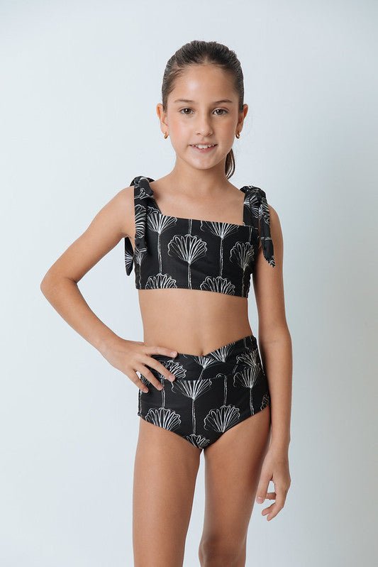 Girl wearing a black and white bikini set. She's standing behind a white background. The purpose of this image is to highlight the swimsuit by Mar de Lua. 