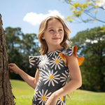 Little girl posing in the swimsuit at a park under a sunny day. She is smiling and looking away from the camera. 
