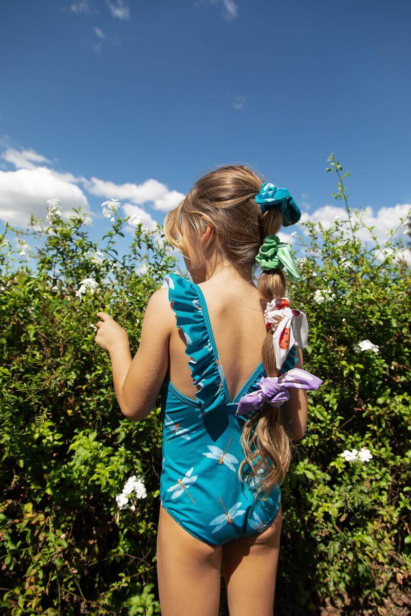 Little girl with her hair up in a ponytail wearing this cute one piece swimsuit.