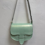 Mint green handbag with a strap on a light gray background
