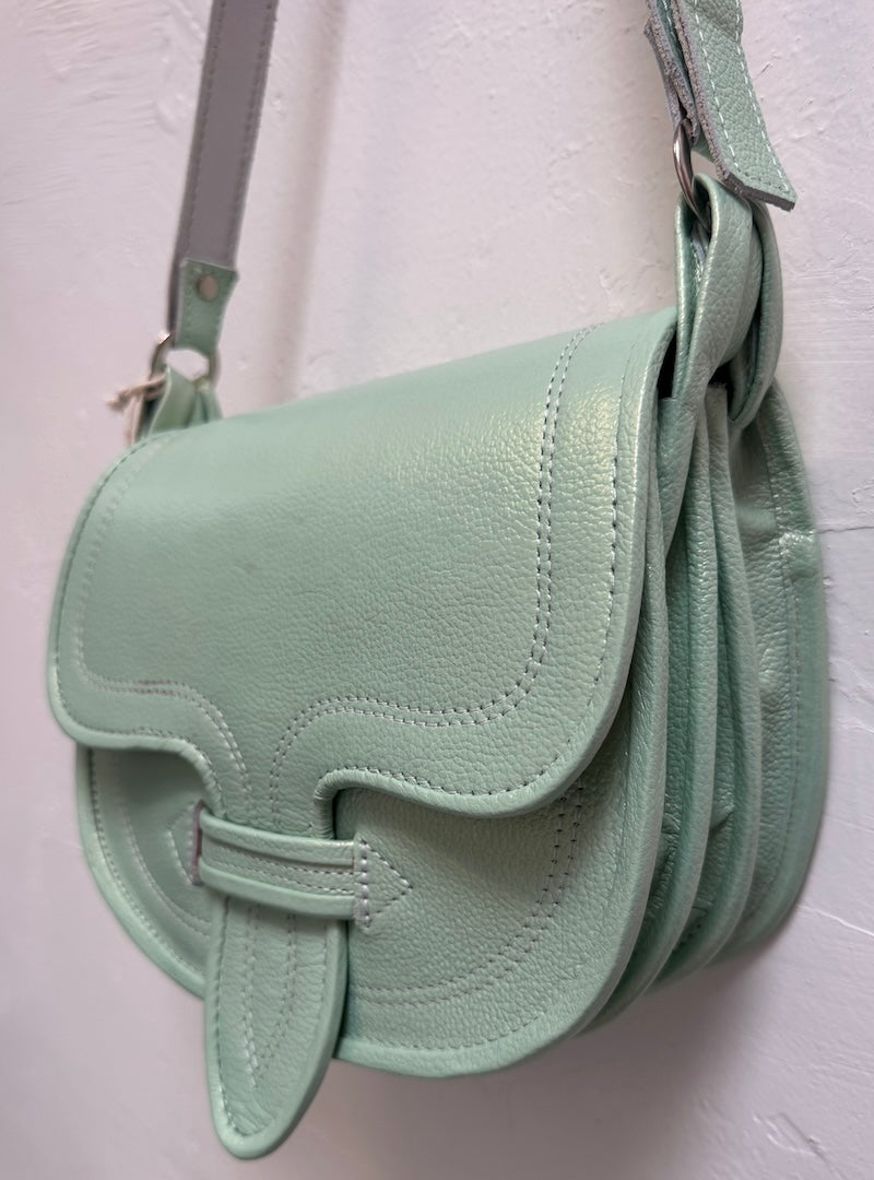 green handbag hanging against a beige wall.