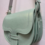 green handbag hanging against a beige wall.