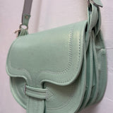 green handbag hanging against a beige wall.