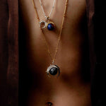 Close up of a model wearing two necklaces with the herradura charm in reclaimed sterling silver, handcrafted in Bogotá.
