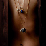Close up of a model wearing two necklaces with the herradura charm in reclaimed sterling silver, handcrafted in Bogotá.