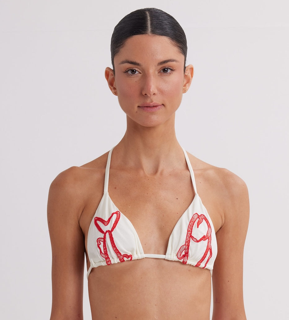 Woman wearing a white bikini top with red lobster prints on a plain background