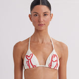 Woman wearing a white bikini top with red lobster prints on a plain background