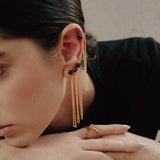 Image of a woman wearing four earrings with a black stone and chains. The purpose of this image is to highlight the jewelry by Pajarolimon.