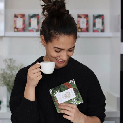 A person drinking coffee while holing Keru Chocolates coffee flavored chocolate bar.