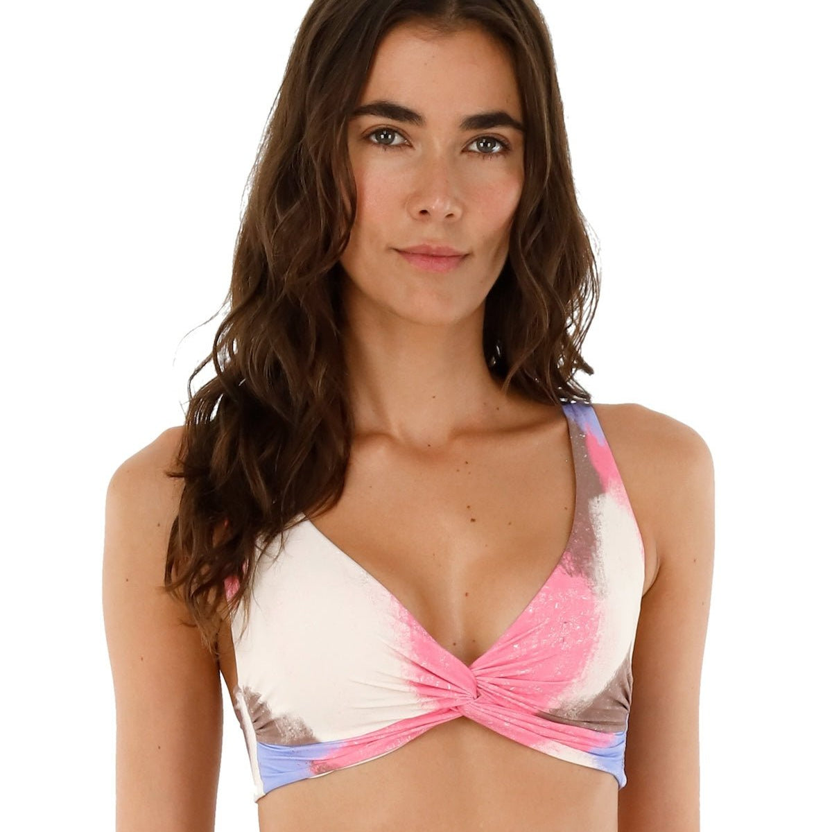 Image of a woman wearing a tie die swimsuit top by Malai Swimwear. She's smiling and standing on a white background. The purpose of this image is to highlight the bikini.