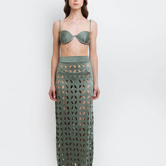 Model wearing a laser cut green skirt by Mar de Lua. She's standing in front of a white background. The purpose of the image is to highlight the skirt because it's for sale at EVAMAIA boutique in Studio City, CA.