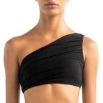 Close-up of a model wearing the Leonor bikini top. It's black and has a drapped one-shoulder look.