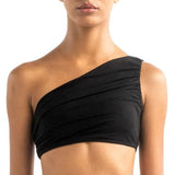 Close-up of a model wearing the Leonor bikini top. It's black and has a drapped one-shoulder look.