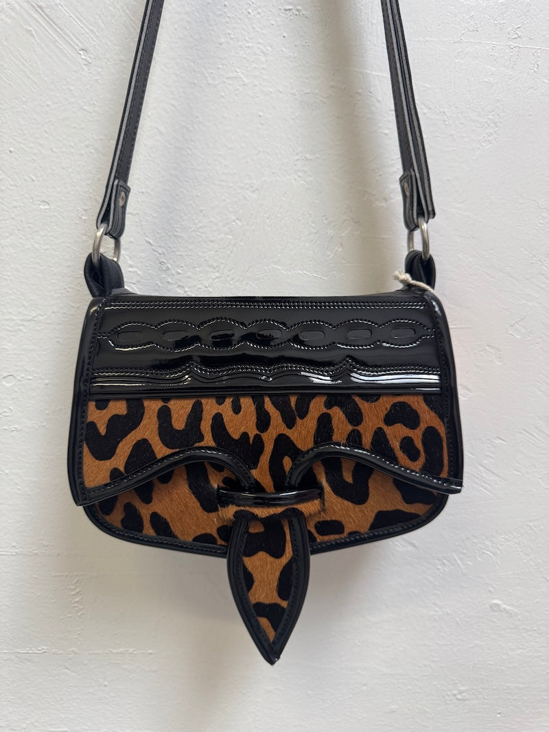 Leopard print handbag with black accents on a white background