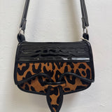 Leopard print handbag with black accents on a white background