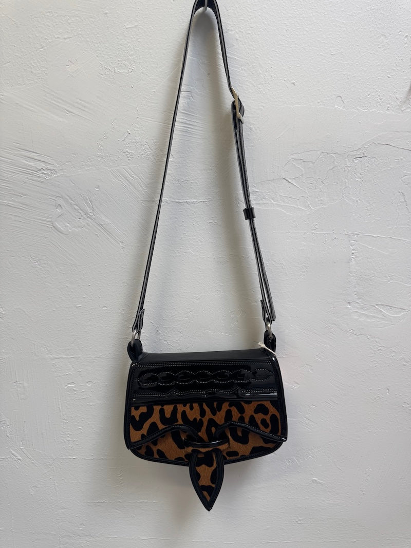 Black handbag with leopard print pattern on a light gray background