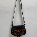 Black handbag with leopard print pattern on a light gray background