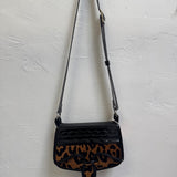 Black handbag with leopard print pattern on a light gray background