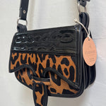 Leopard print handbag with black accents on a white background