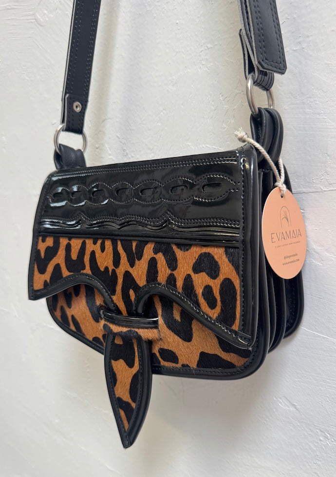 Leopard print handbag with black accents on a white background
