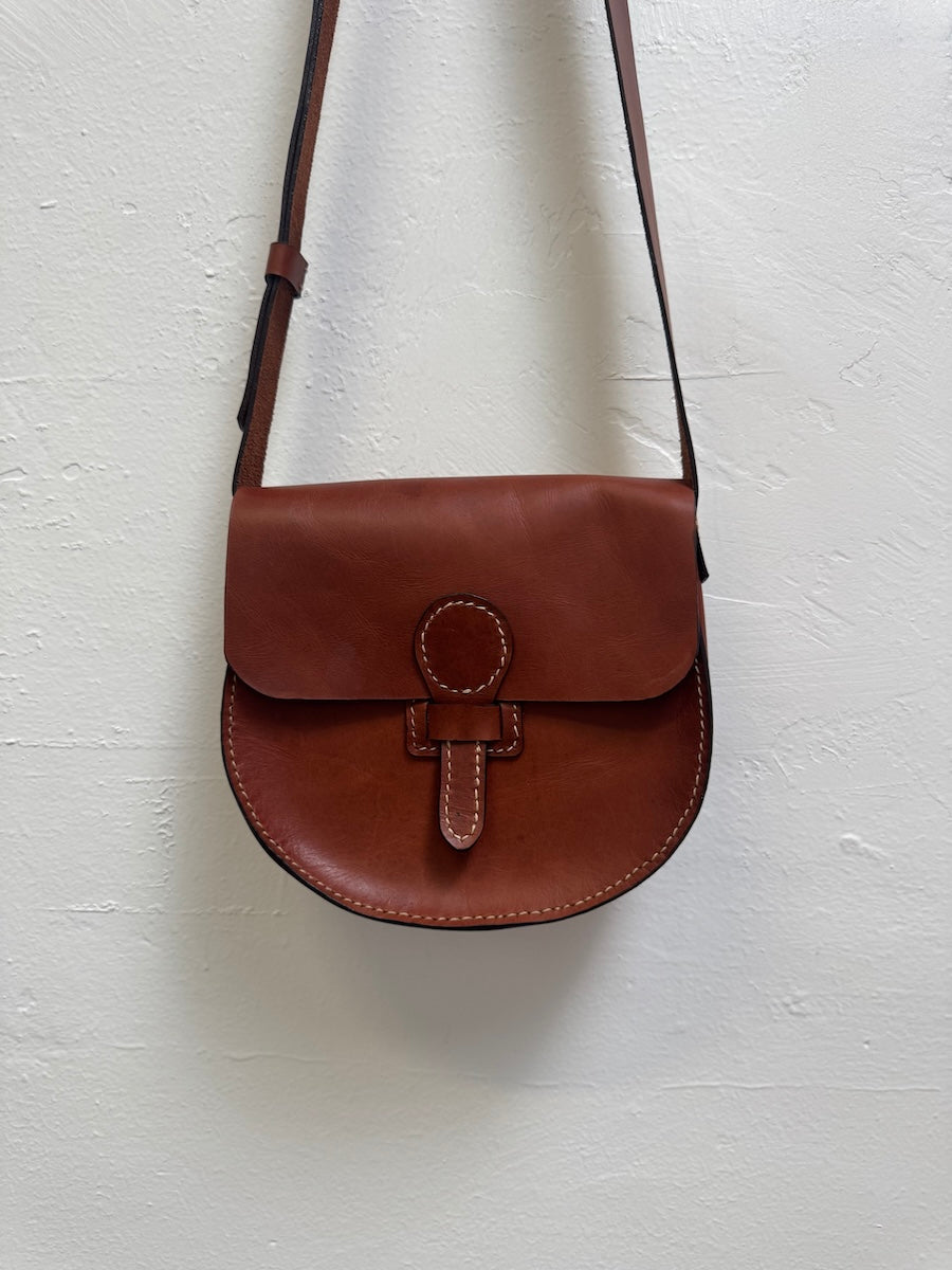 Brown leather bag with a strap on a white background