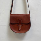 Brown leather bag with a strap on a white background
