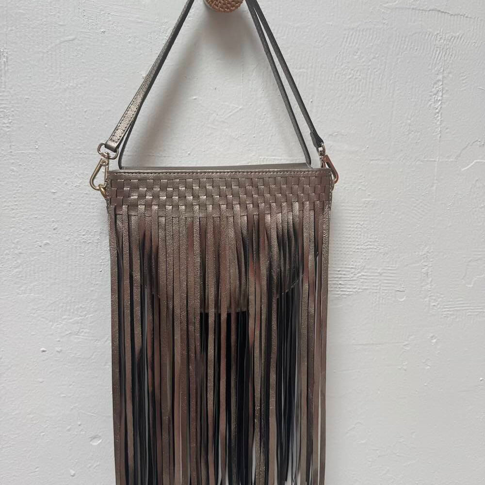 Metallic gold woven handbag with fringe on a white background.