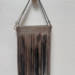 Metallic gold woven handbag with fringe on a white background.