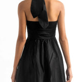 Close up image of the back of a woman wearing a black mini halter dress by Encanrtadore Swimwear. It's against a white background. The purpose of this image is to highlight the dress because it is sold at EVAMAIA boutique in Studio City, CA.