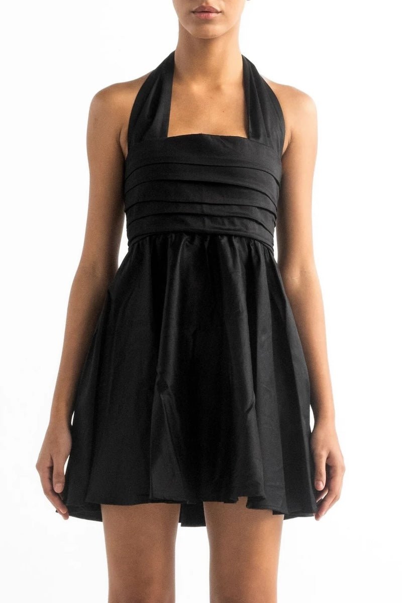 Close up image of a woman wearing a black mini halter dress by Encanrtadore Swimwear. It's against a white background. The purpose of this image is to highlight the dress because it is sold at EVAMAIA boutique in Studio City, CA. 