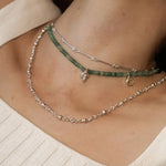 Woman wearing a short green quartz beaded necklace layered with a fine silver chain