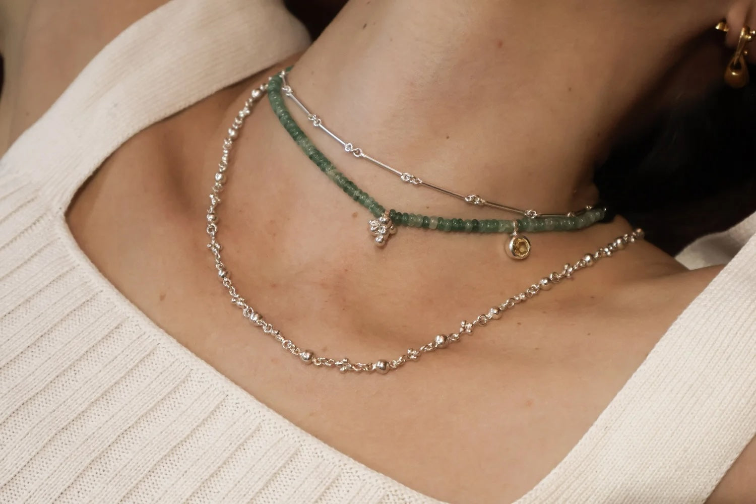 Woman wearing a short green quartz beaded necklace layered with a fine silver chain
