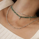 Woman wearing a short green quartz beaded necklace layered with a fine silver chain