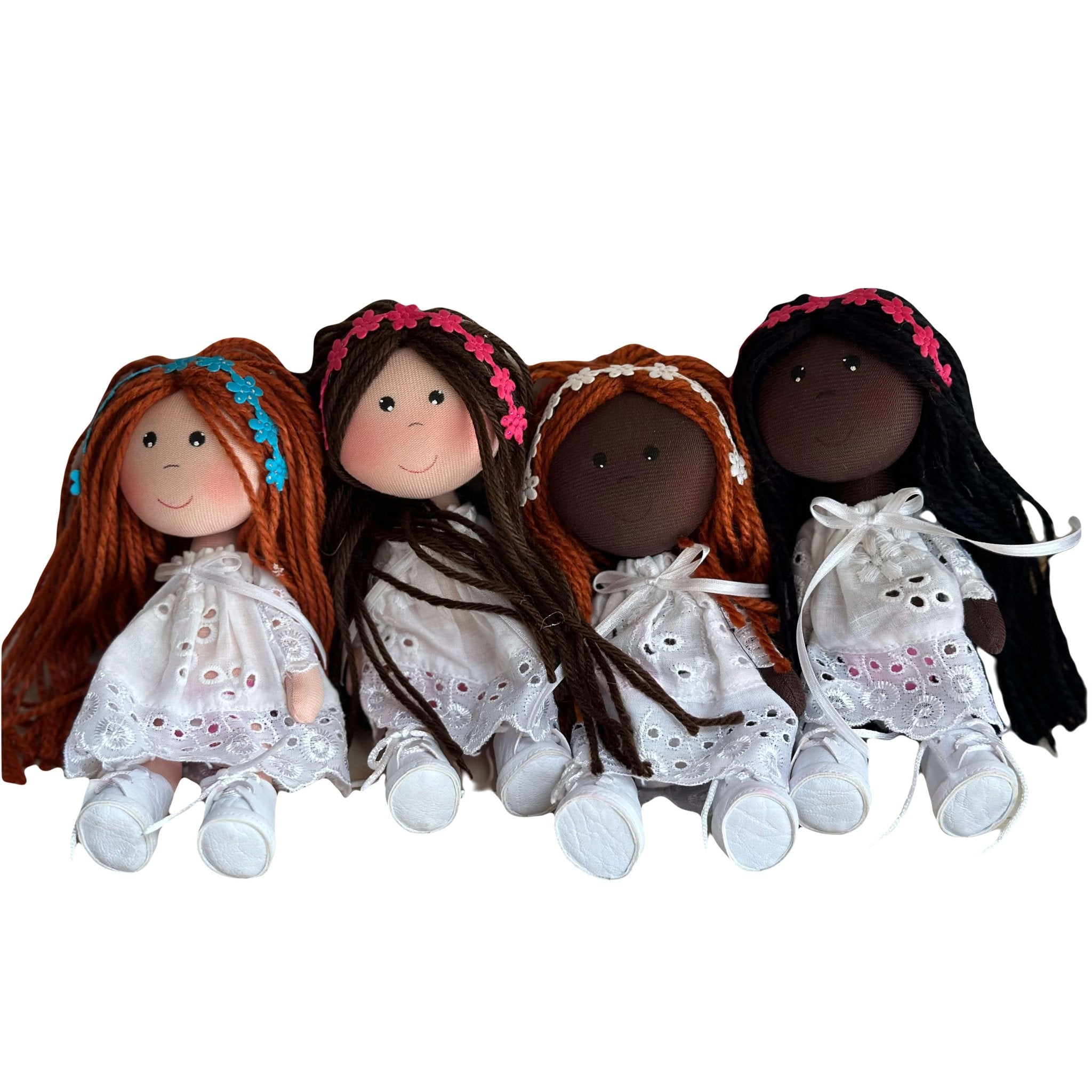 Cute rag dolls handmade in Colombia. There are 4 dolls wearing a white crochet dress with different skin and hair colors. They are also wearing flower headbands.