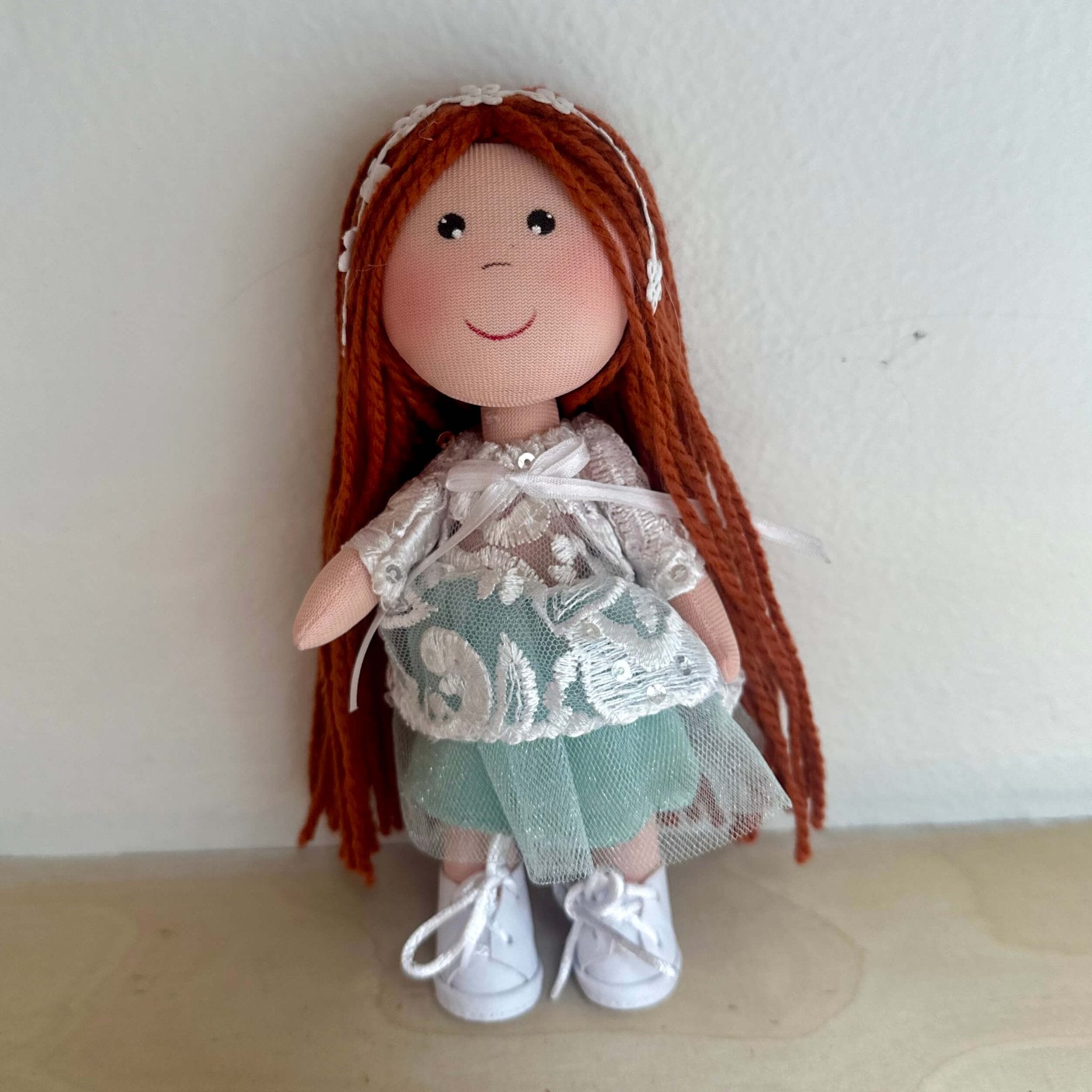 Cute rag doll handmade in Colombia. There is a doll wearing a white/mint green tutu dress with red hair. She is also wearing a flower headbands.