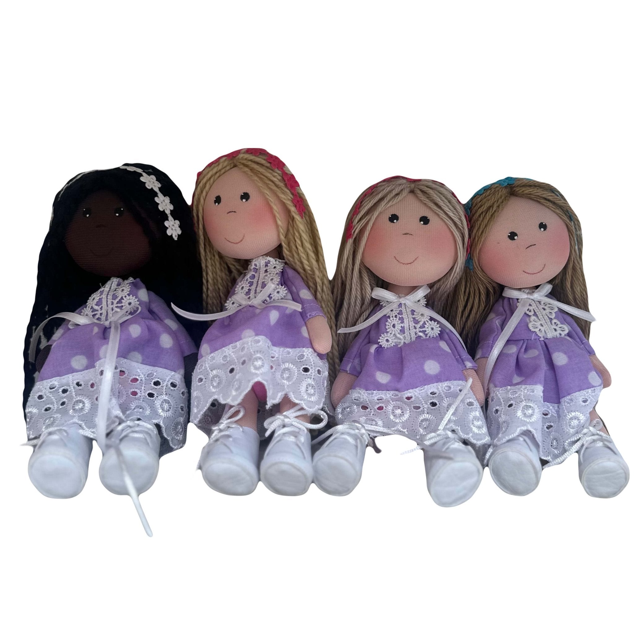 Cute rag dolls handmade in Colombia. There are 4 dolls wearing a purple polka dot dress with different skin and hair colors. They are also wearing flower headbands.