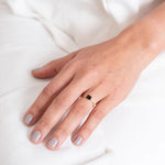 Close up image of a woman's hand wearing a dainty gold ring with a raw black tourmaline stone on it. The purpose of this image is to highlight the ring because it is for sale at EVAMAIA boutique in Studio City, CA and online.