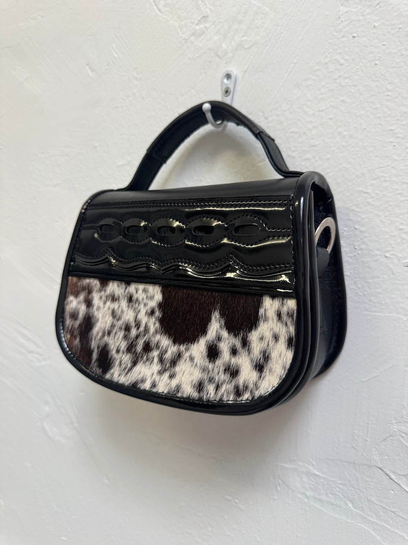 Handbag with black and white cowhide pattern on a white background