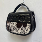 Handbag with black and white cowhide pattern on a white background