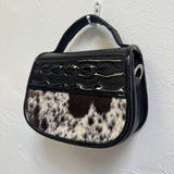 Handbag with black and white cowhide pattern on a white background
