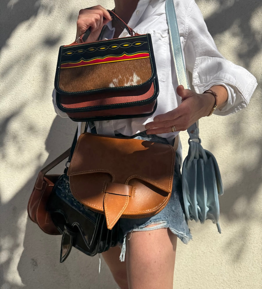 Person holding carriel leather bags with decorative patterns against a neutral background