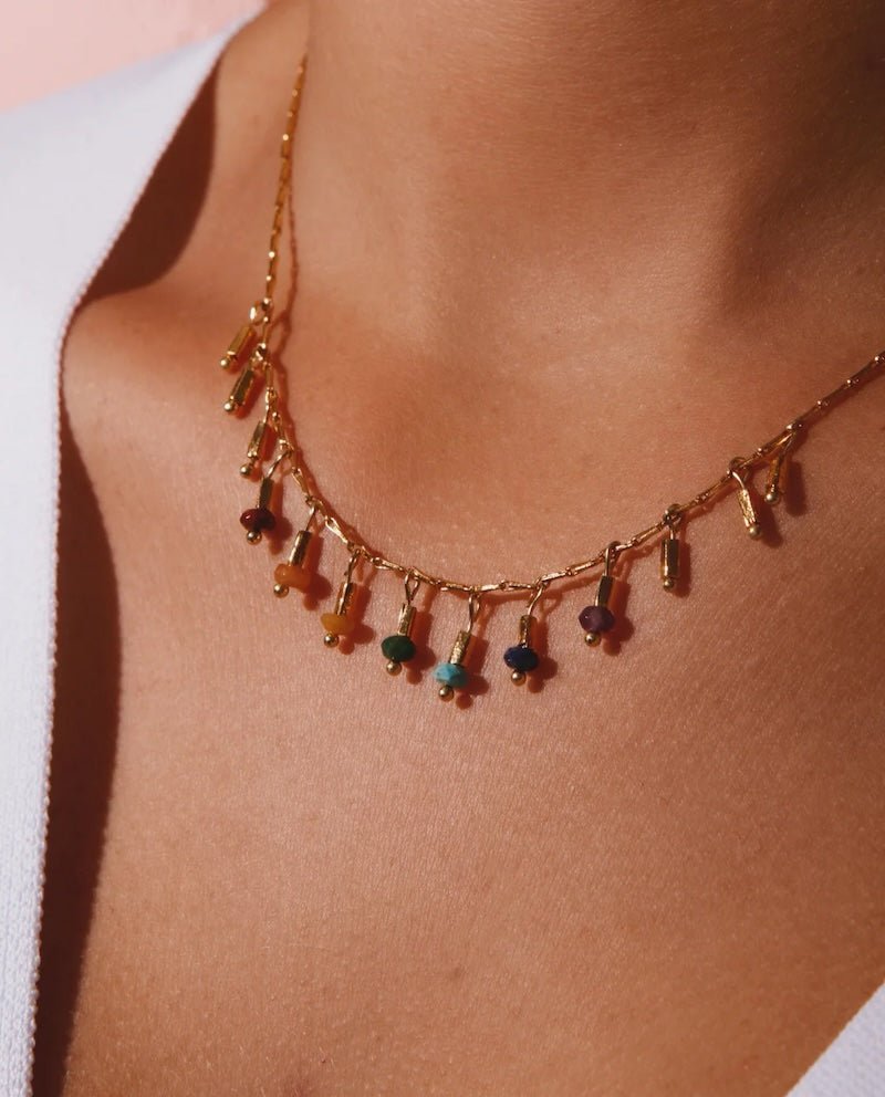 Close up image of a woman wearing a dainty necklace with 7 stones representing the chakras. The purpose of this image is to highlight the necklace, which we sell at EVAMIA boutique in Studio City, CA and online.